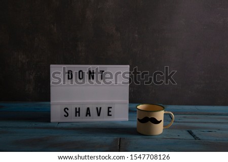 Visual Lightbox with the words dont shave and a cup with mustache on vintage blue wooden background