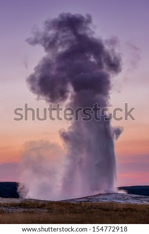 Old Faithful Geyser erupts just after sunset at the Upper Geyser Basin of Yellowstone National Park, Wyoming Royalty-Free Stock Photo #154772918