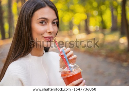 Close up picture of a young woman taking a plastic straw of her drink