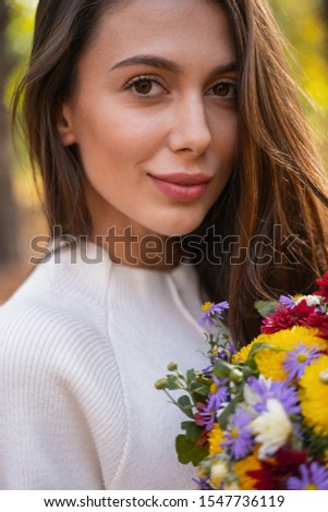 Close up picture of a beautiful woman with a bunch of different flowers