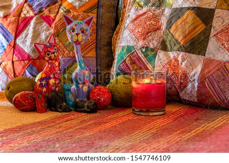 decorative composition of multicolored cats surrounded by pears and eggs in the light of a candle and in the background multicolored cushions.