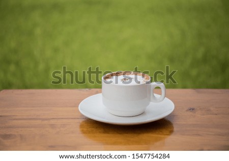 A white coffee cup on a wooden table With a backdrop of rice fields