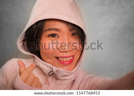 young beautiful and happy Asian Korean student woman taking selfie portrait photo for using social media app enjoying playful smiling gesturing sweet in hipster style hood on isolated background