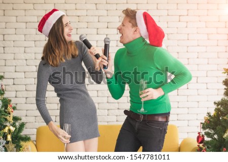 Close up shot of lovely Caucasian couple celebrates their Christmas by singing fun songs and dancing this festive season.