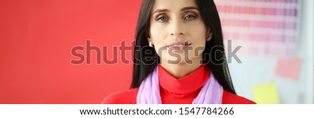Serious brunette business lady in red dress portrait. Looking at camera against modern office background. Career in successful company concept. Distance education people.