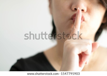 Close-up image of woman use index finger of the right hand touching on lips for sending a signal telling to keep quiet; or telling to keep secret. (soft focus)