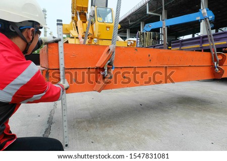 Engineer conducting safety inspection and load test on the wire sling which attached with crane lifting hook prior use in the construction project area. Royalty-Free Stock Photo #1547831081