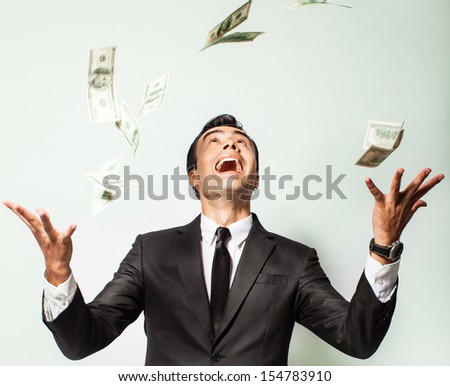 Businessman rejoicing for his success with hundred dollar bills. Money rain.