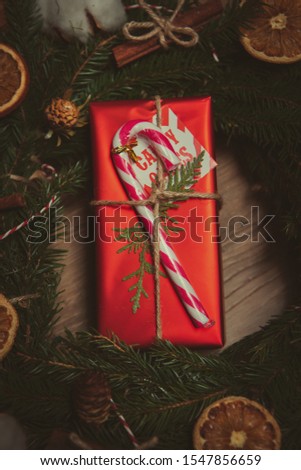Happy New Year 2020 presents in close up.Red decorative gift box with Christmas stick candy bar and fir tree branches shot in close up from above