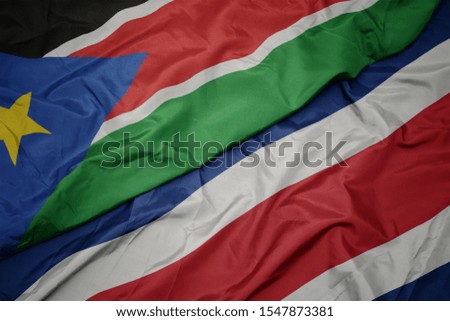 waving colorful flag of costa rica and national flag of south sudan. macro