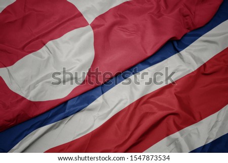 waving colorful flag of costa rica and national flag of greenland. macro