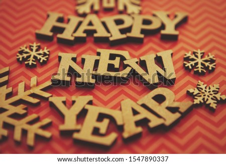 Happy New Year background.Red stripped backdrop and rustic wooden letters edited with old film filter.Winter holiday wallpaper in vintage style