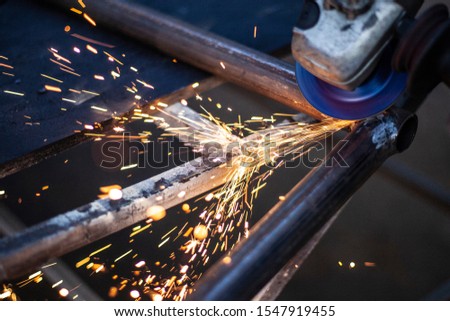Metal processing in the workshop. Grinding metal. The worker makes the structure of a metal profile. Creating a shelving for the city dweller. Sparks from metal friction.