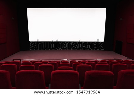 Empty of cinema in red color with white blank screen. Mockup of hall, no people and auditorium