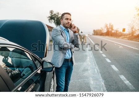 Elegant middle age business man calling towing service for help on the road. Roadside assistance concept. Royalty-Free Stock Photo #1547926079