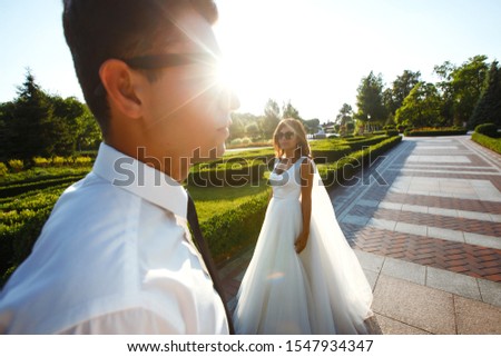 Married couple having fun. Groom in a stylish suit and bride in a beautiful white dress, the couple is walking in the park on their wedding day. Kissing, having fun, dancing, happiness.