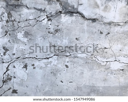 gray cracked wall with large cracks over the entire surface, full frame
