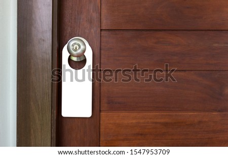 Door Hanger Acrylic Shape Blank on dark wooden door background. 
for your mock up and advertising design.