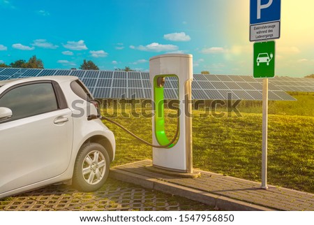 Electric filling station electric car white solar system translation parking lot sign: "electric vehicles during charging" (German)