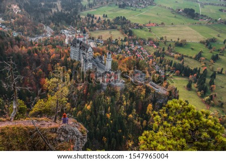 Young woman looking at the famous royal castles of Neuschwanstein and Hohenschwangau in the autumn season. Vacation in mountains. Alps. Bavaria. Germany. 