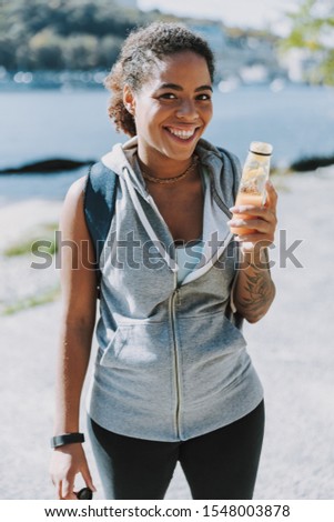 Beautiful young lady with drink looking at camera and smiling stock photo