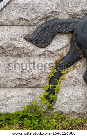 Ivy wraps up and grows, black horse hind leg carved on the wall