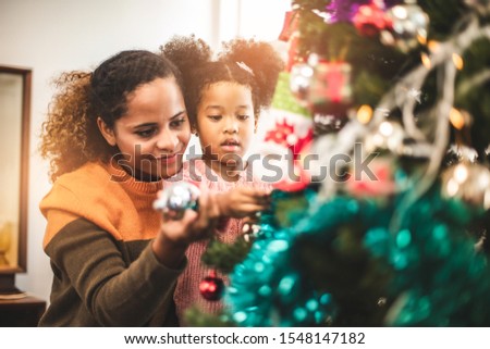 Merry Christmas and Happy Holiday. Mom and daughter decorate the Christmas tree . The morning before Xmas. .Happy little smiling girl .
