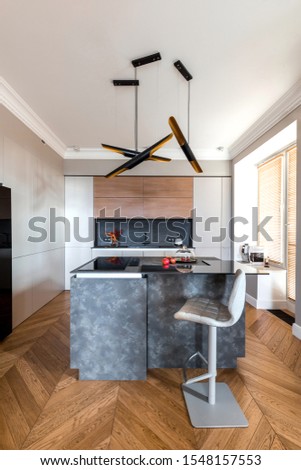 Minimalist wooden grey kitchen with handleless facades, impressive lamp, kitchen island and autumn decor, smart storage system. Kitchen room organization