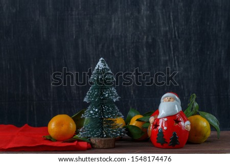 toy Christmas tree and Santa with tangerines on dark background