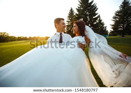Groom circling bride in beautiful white dress at sunset. Lovely wedding couple at sunset. Gorgeous bride and handsome groom. Together. Young family. Marriage. Romantic moment. Wedding concept.
