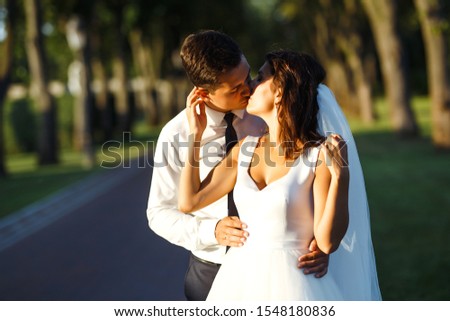 Young wedding couple enjoying romantic moments. A stylish bridegroom in a black suit gently embraces a beautiful bride in a white dress. Relationship love concept. Together. Young family. Marriage.  