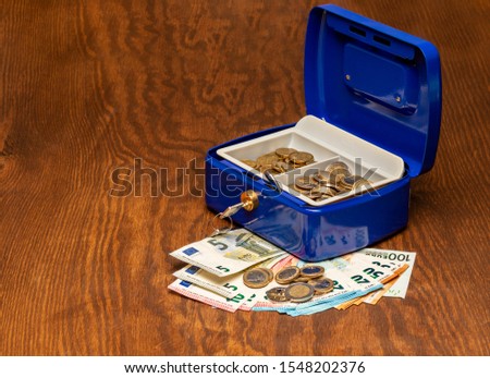 Blue cash box with cash on a table