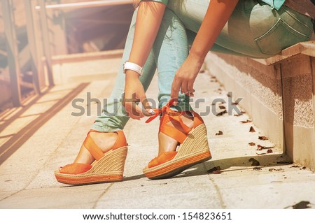 girl sits and orange bow tying on their sandals Royalty-Free Stock Photo #154823651