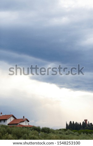 Italy, Tuscany. Dramatic cloudy sky. Endless fields, small white houses with red roof. Autumn, October. Copy space for text