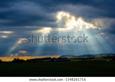 Beautiful landscape with dark clouds and beams of light coming through the sky in Scotland  Royalty-Free Stock Photo #1548261716