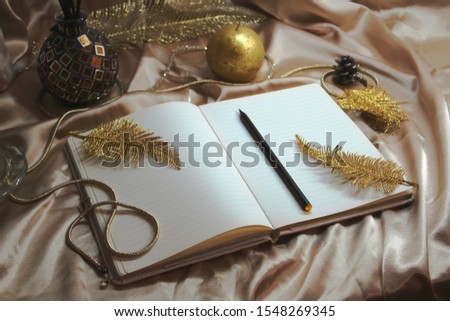 Christmas time, xmas decoration, happy new year 2022, 2023 golden notebook, bucket list, to do list and plans, candle on the table with the silk and feathers, warm winter cozy interior,letter to Santa
