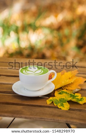 Cup of matcha green tea on wood table at cafe. Trendy powered tea. Greenery pantone.