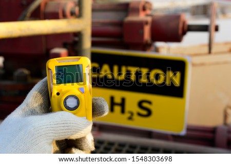 Oilfield technician checking H2S gas with his pocket type H2S Gas detector at well head in oilfield  Royalty-Free Stock Photo #1548303698