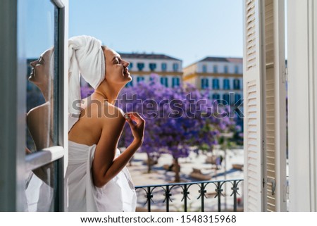 girl laughing on a hotel balcony on a background of flowering trees