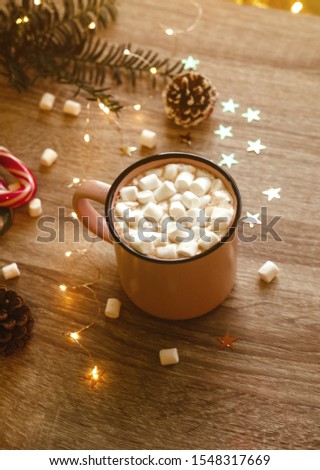 Christmas moody picture with pink cup of coffee with marshmallows and confetti on wooden background