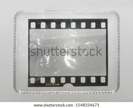 empty or blank 35mm filmstrip behind collector's plastic holder on white background with scratches, trading card holder with film snip in it, just blend in your content here, cool placeholder