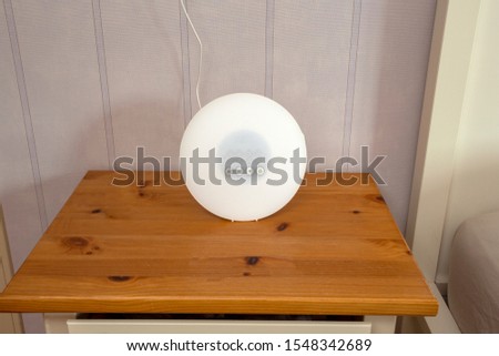 Wake-up light modern alarm on wooden night stand in retro living room closeup