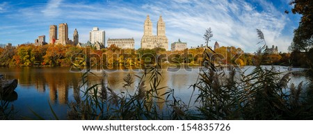 Urban view of Manhattan, New York, from the Lake in Central Park in autumn. The morning light enhances the colorful trees and plays on the water surface reflecting Upper West Side buildings. Panoramic