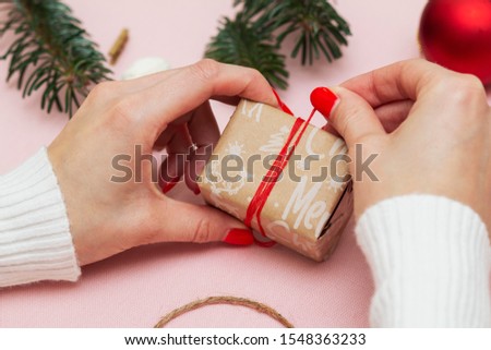 handmade gift wrapping and decorating a gift wrapped in festive paper with the inscription Christmas