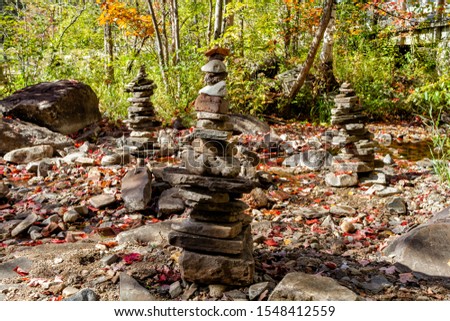 Pebbles, stacked stones as stone statues on the Muskoka river bay, Ontario, short depth of field, forest on background.