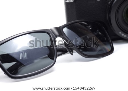 Black camera and sunglasses on a white isolated background