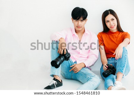 Portrait of young male photographer sitting and posting with beautiful model in studio for memory photo taking shot.