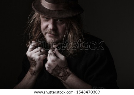 henna man in a brown hat with long hair and drawings