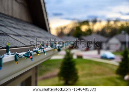 Hanging Christmas lights on gutter with plastic clips Royalty-Free Stock Photo #1548485393