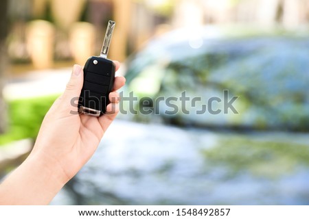 Woman holding key near new car outdoors, closeup. Space for text